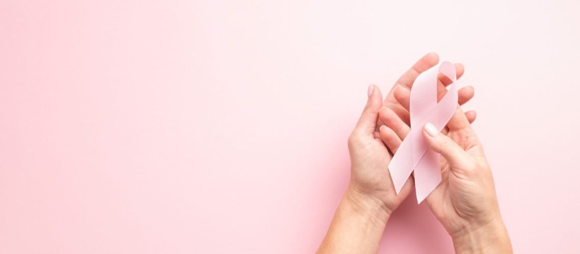 World Breast Cancer Awareness Month card with female's hands and pink ribbon..